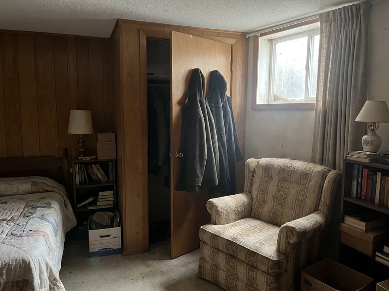 Stale basement guest room with an armchair and closet
